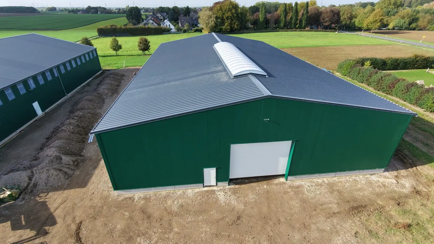 Fertige Halle mit dunkelgrüner Paneelfassade und Firstlichtband aus der Vogelperspektive